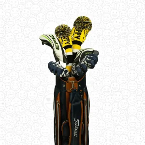 A golfer with a golf bag, showcasing the Happy Gilmore-inspired knitted golf headcovers (driver and fairway wood) in a lifestyle setting, with a humorous "HAPPY" design in yellow, black and white.